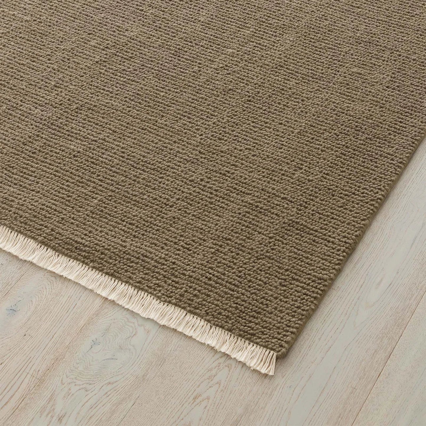 Sandy Beige rug with a textured pattern and fringe on a wooden floor. 2x3 3x4. 100% NZ wool