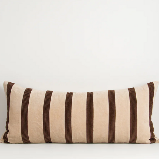 A richly textured patchwork cushion combining velvet and corduroy in warm cherry tones on a deep chocolate base.
