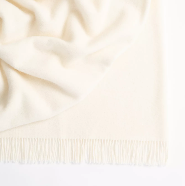 Shop the Nevis lambswool throw 130x200cm – made from 100% New Zealand wool with a soft, thick texture and tassel fringe, perfect for cosy living and gifting.