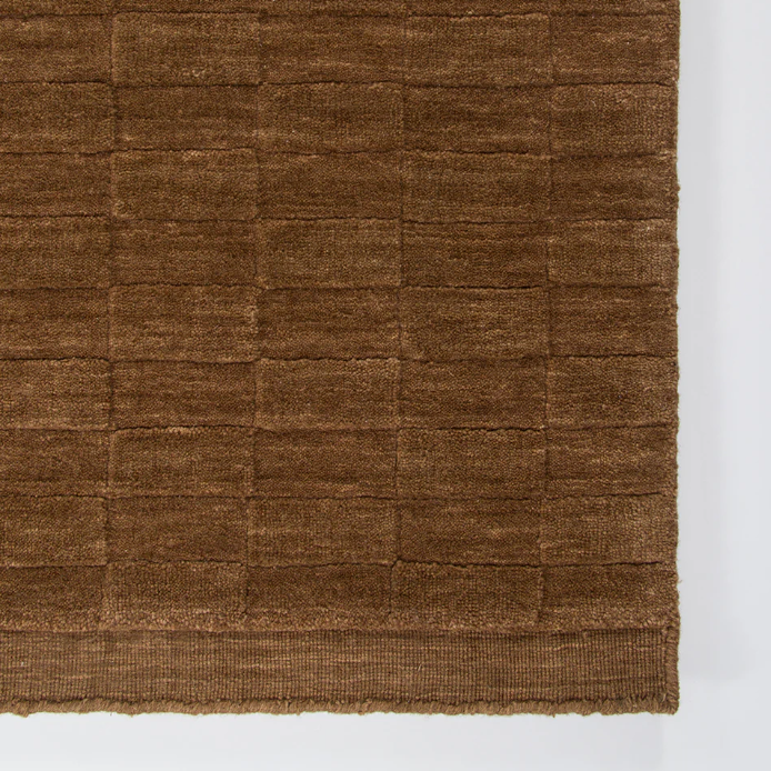 A handcrafted wool rug featuring a sculptural checkerboard design, bringing depth, texture, and bold sophistication to contemporary interiors.