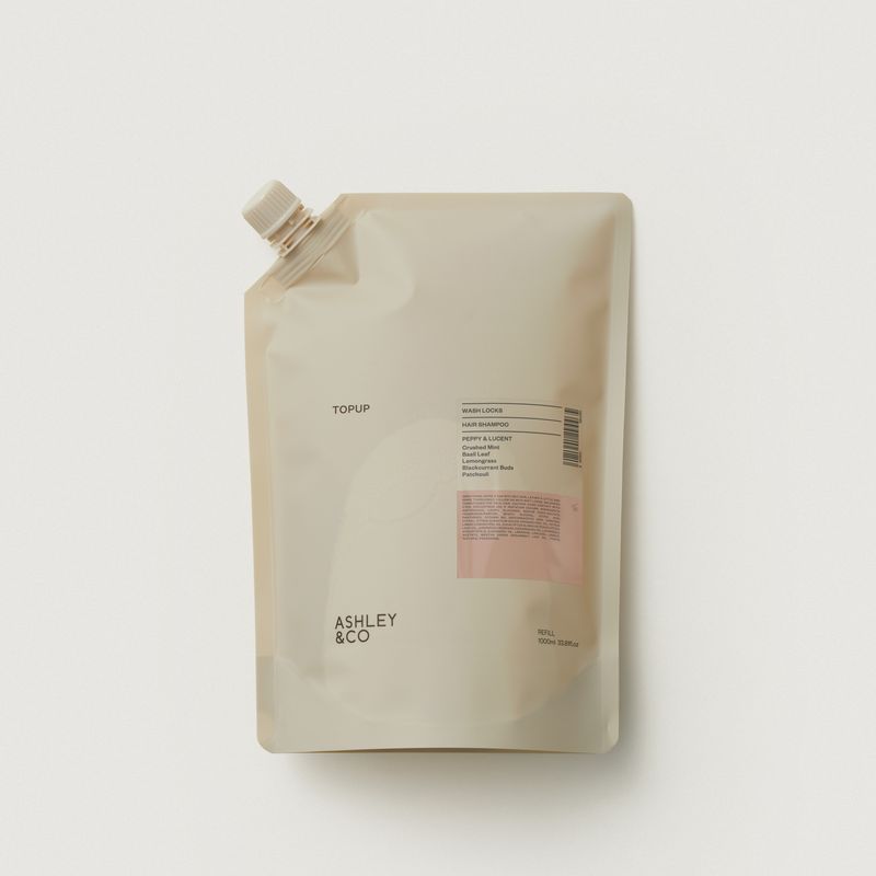 A refill pouch with a white flip-top cap, featuring a minimalist design in warm beige with a small pink label block and black text, including the brand name 'ASHLEY & CO'.