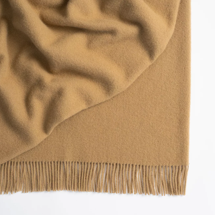Shop the Nevis lambswool throw 130x200cm – made from 100% New Zealand wool with a soft, thick texture and tassel fringe, perfect for cosy living and gifting.