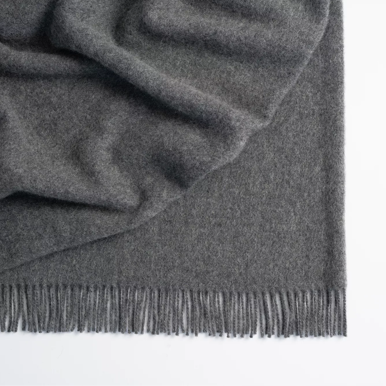 Shop the Nevis lambswool throw 130x200cm – made from 100% New Zealand wool with a soft, thick texture and tassel fringe, perfect for cosy living and gifting.