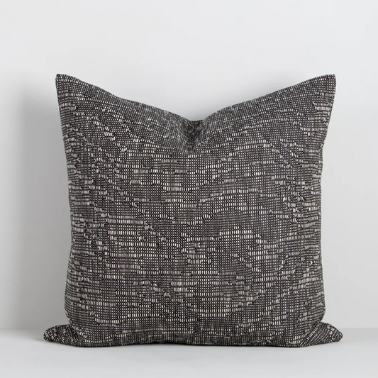 The Adler 55x55cm cushion features a subtle flecked weave in warm tones, adding refined texture and versatility to your interior styling.