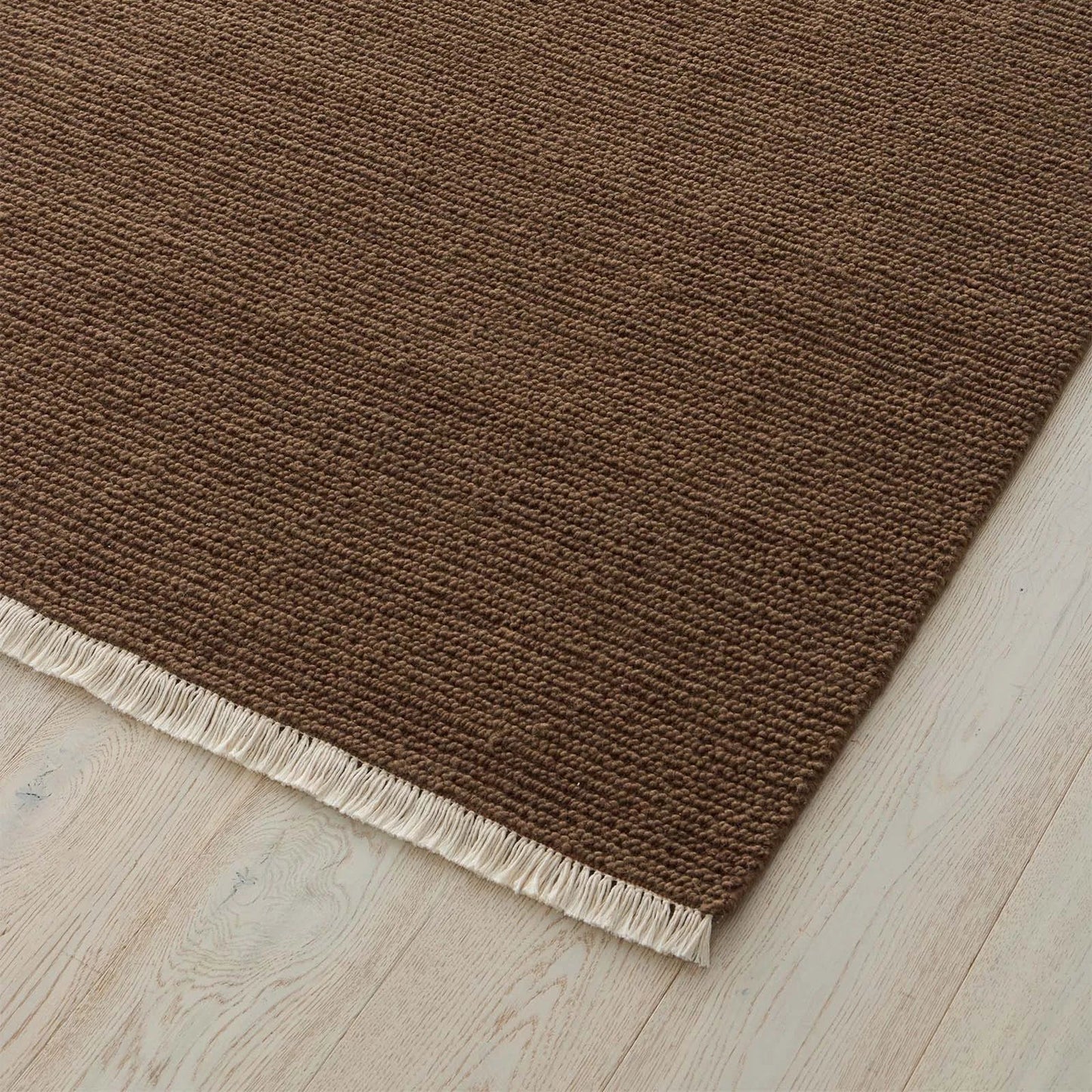Rich clay toned rug with a textured pattern and fringe on a wooden floor. 2x3 3x4. 100% NZ wool
