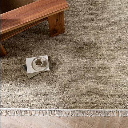 Brown textured rug with a wooden bench and coffee cup on a wooden floor. 100% NZ Wool