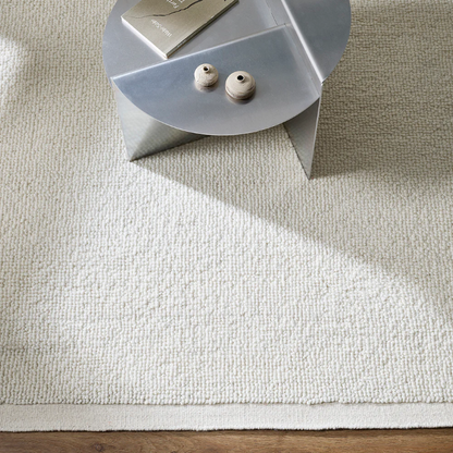 Beige rug on a wooden floor with a small round table in the corner. 100% NZ Wool