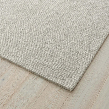 Close-up of a textured light grey rug on a wooden floor. 2x3. 100% nz wool