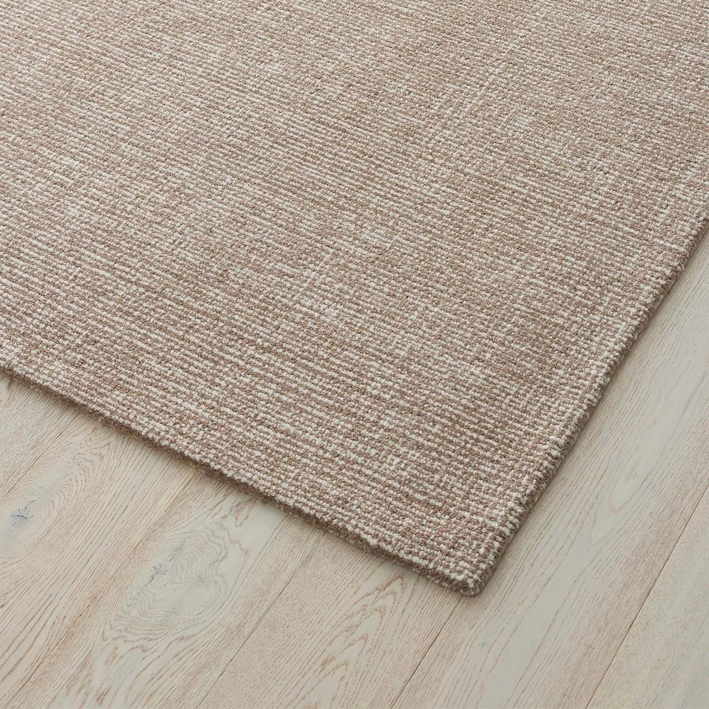 light brown textured rug on a wooden floor. 2x3. 100% nz Wool