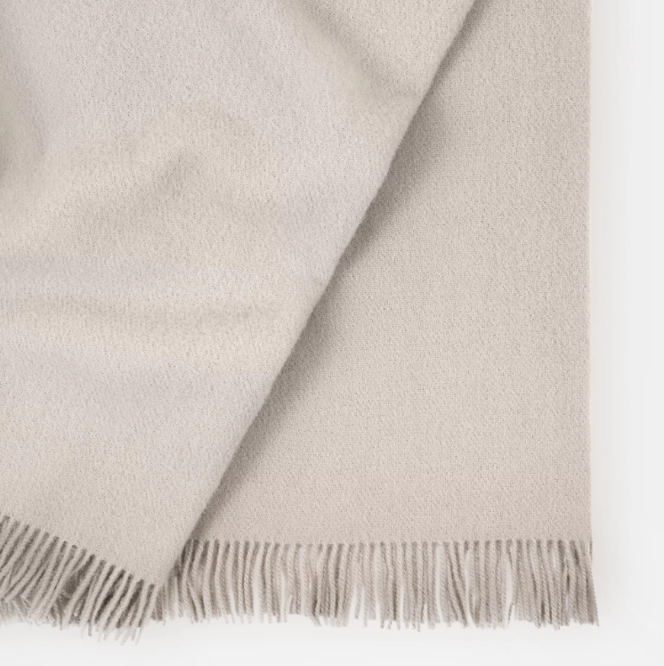 Shop the Nevis lambswool throw 130x200cm – made from 100% New Zealand wool with a soft, thick texture and tassel fringe, perfect for cosy living and gifting.