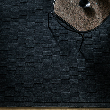 A handcrafted wool rug featuring a sculptural checkerboard design, bringing depth, texture, and bold sophistication to contemporary interiors.