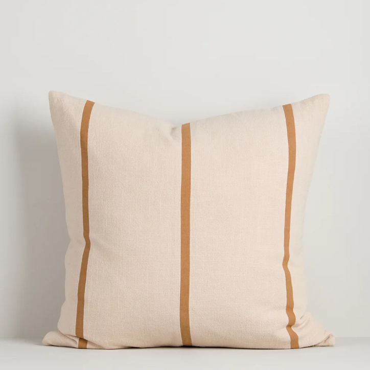 A contemporary cotton cushion featuring bold appliqué stripes in warm caramel tones, designed to add texture and character to modern interiors.