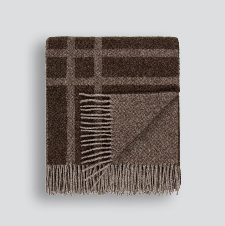 A timeless wool throw with a refined plaid design, crafted from 100% New Zealand lambswool for warmth and comfort.