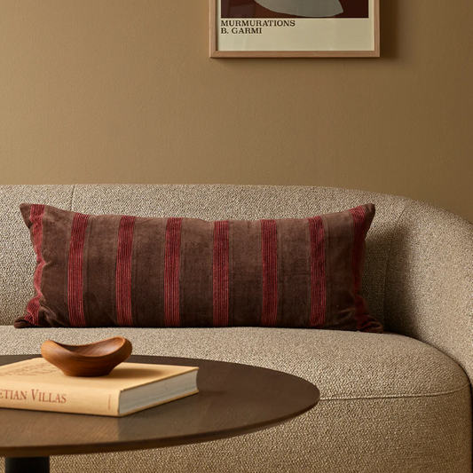 A richly textured patchwork cushion combining velvet and corduroy in warm cherry tones on a deep chocolate base.