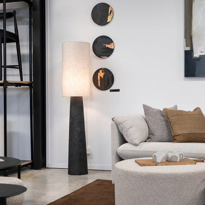 Modern living room with a gray sectional sofa, round ottoman, and abstract art on the wall.