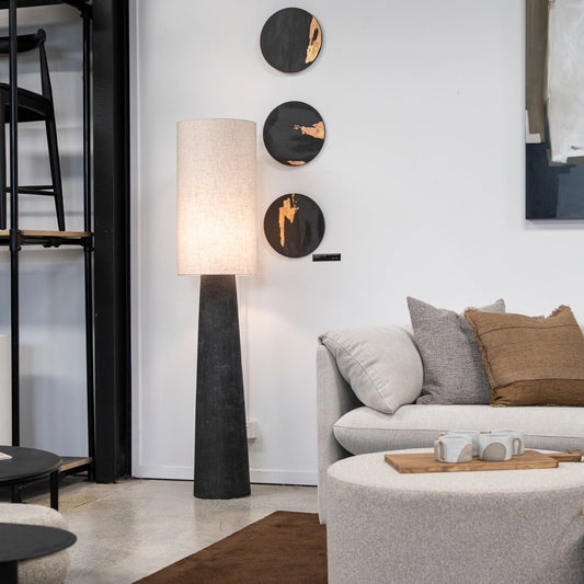 Modern living room with a gray sectional sofa, round ottoman, and abstract art on the wall.