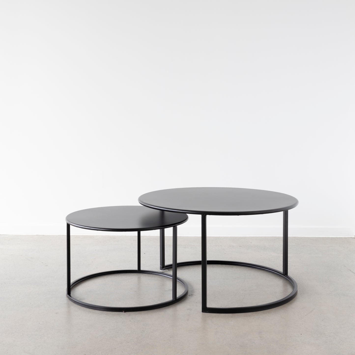 A minimal and stylish set of 2 round coffee tables in black iron. Designed so that the smaller size fits completely under the larger one you can place these together or separate them when entertaining. 
