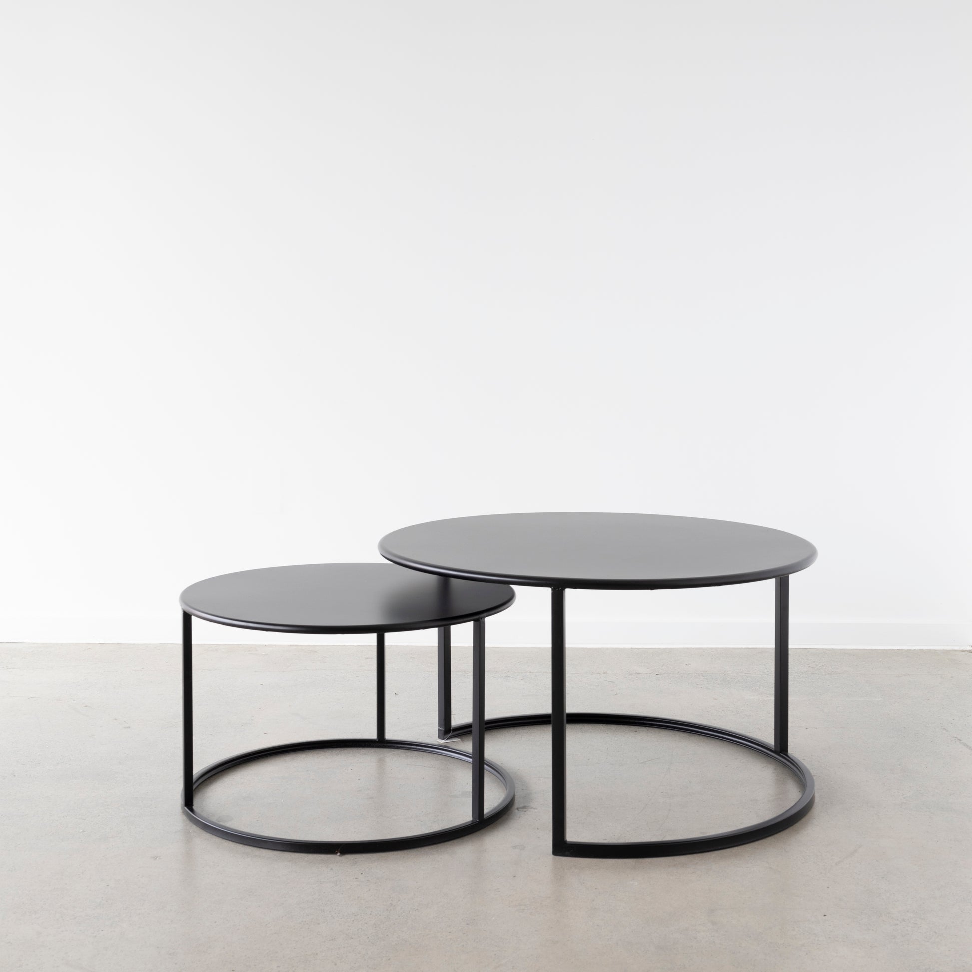 A minimal and stylish set of 2 round coffee tables in black iron. Designed so that the smaller size fits completely under the larger one you can place these together or separate them when entertaining. 